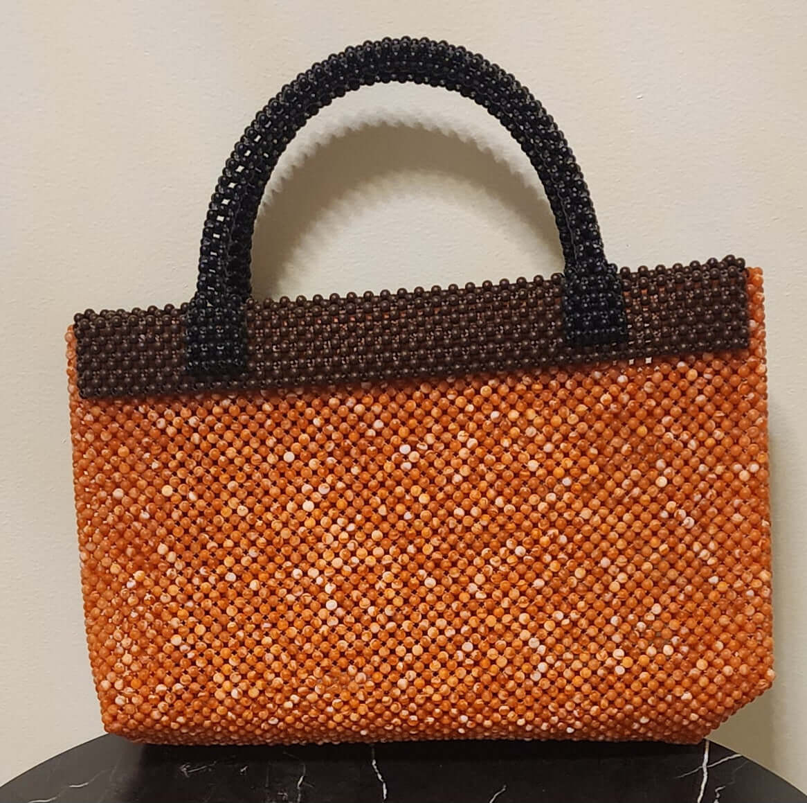 "Theresa Exotic Carry Around luxury designer bag with beaded orange and brown pattern and black handles"